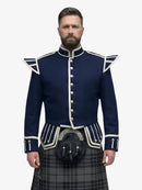 Man wearing a blue military-style jacket with white trim and a grey watch tartan kilt on a white background