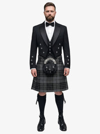 Man wearing a traditional Scottish grey watch tartan kilt with a black prince charlie jacket on a white background