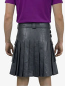 Person wearing a black pleated leather kilt over a purple shirt on a white background