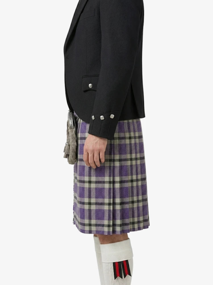 Person wearing a black blazer and purple plaid kilt on a white background
