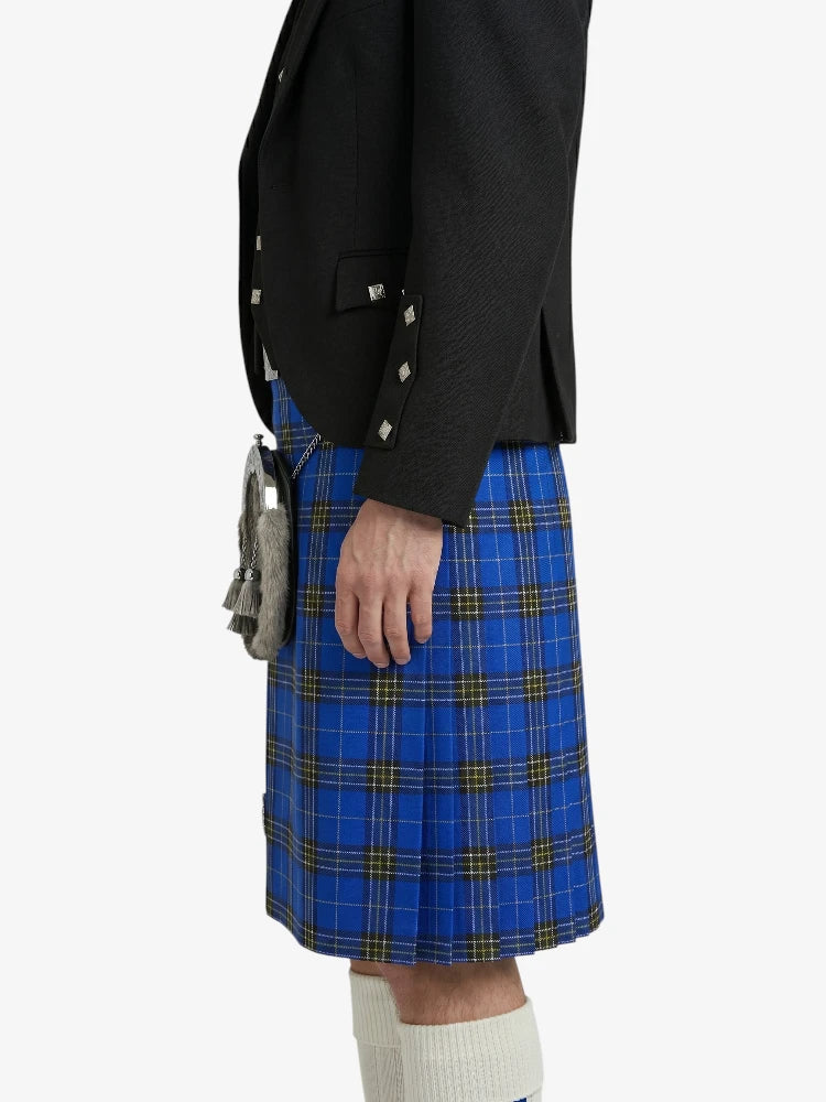 Person wearing a black blazer and blue plaid kilt on a white background