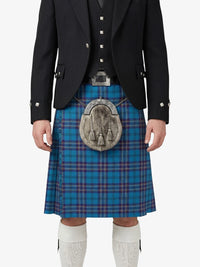 Person wearing a traditional Scottish kilt with a blue plaid pattern on a white background