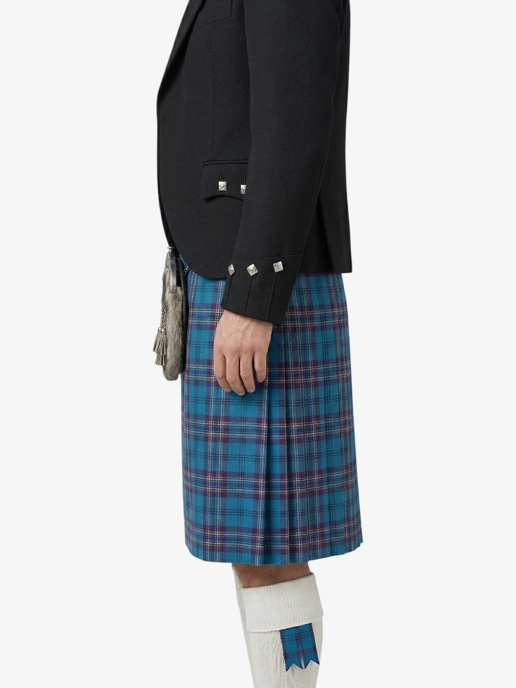 Person wearing a black blazer and blue plaid kilt on a white background