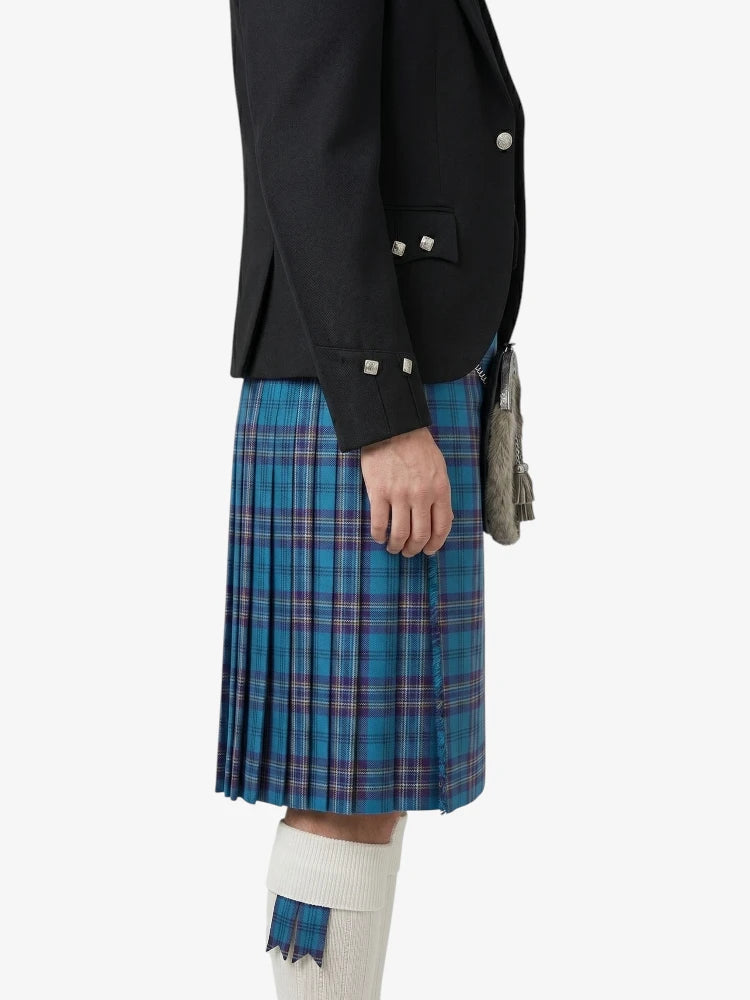 Person wearing a black jacket and blue plaid kilt on a white background