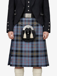 Person wearing a traditional Scottish kilt with a tartan pattern on a white background