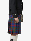 Person wearing a black jacket and a red and blue plaid kilt on a white background