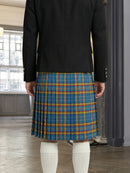 Person wearing a black jacket and blue plaid kilt indoors.