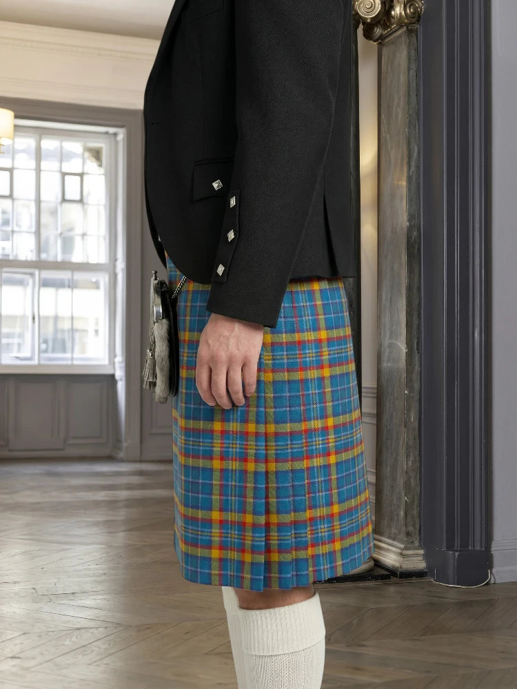 Person wearing a black jacket and blue plaid kilt in an indoor setting.