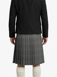 Person wearing a black blazer and gray pleated skirt on a white background