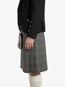 Person wearing a black blazer and gray plaid kilt on a white background