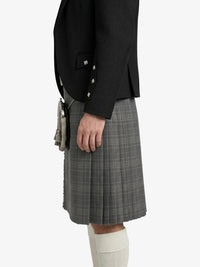Person wearing a black blazer and gray plaid kilt on a white background
