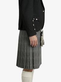 Person wearing a black blazer and gray pleated kilt on a white background