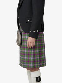 Person wearing a black jacket and green plaid kilt on a white background