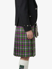 Person wearing a black jacket and a green and purple plaid kilt on a white background