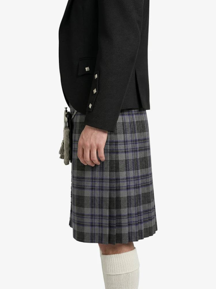 Person wearing a black blazer and plaid kilt on a white background