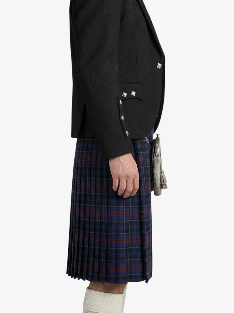 Person wearing a black blazer and plaid kilt on a white background
