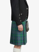 Person wearing a black jacket and green plaid kilt on a white background