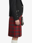 Person wearing a black blazer and red plaid kilt on a white background