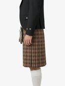 Person wearing a black jacket and plaid kilt on a white background