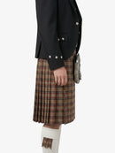 Person wearing a black blazer and plaid kilt on a white background