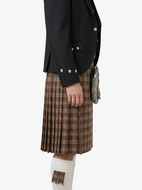 Person wearing a black blazer and plaid kilt on a white background