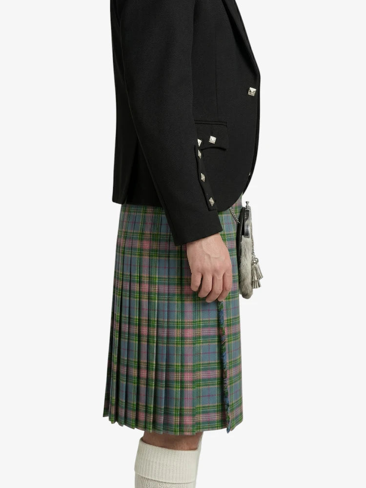 Person wearing a black blazer and plaid kilt on a white background