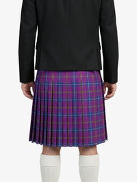 Person wearing a black jacket and purple plaid kilt on a white background