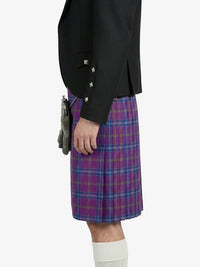 Person wearing a black jacket and purple plaid kilt on a white background