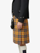 Person wearing a black jacket and yellow plaid kilt on a white background