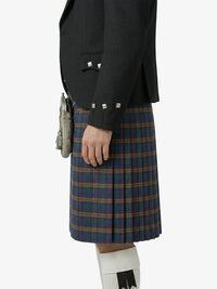 Person wearing a black jacket and blue plaid kilt on a white background