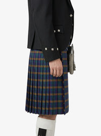 Person wearing a black jacket and plaid kilt on a white background
