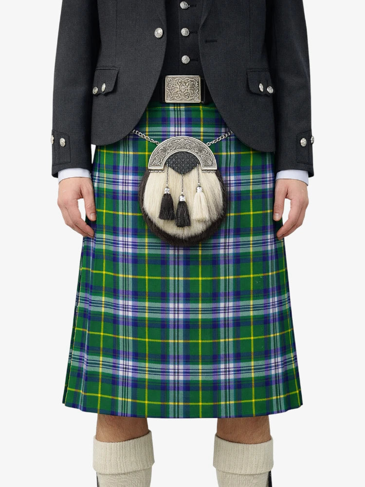 Person wearing a green plaid kilt with a black jacket and white socks on a white background