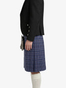 Person wearing a black blazer and blue plaid kilt on a white background