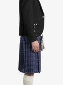 Person wearing a black blazer and blue plaid kilt on a white background
