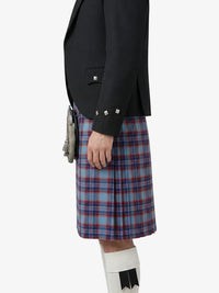 Person wearing a black jacket and blue plaid kilt on a white background