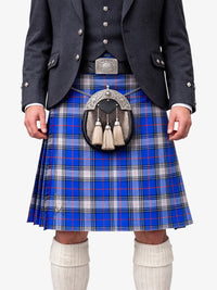 Person wearing a blue plaid kilt with a dark jacket and white socks on a white background