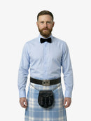 Man wearing a light blue shirt, black bow tie, and plaid kilt on a white background