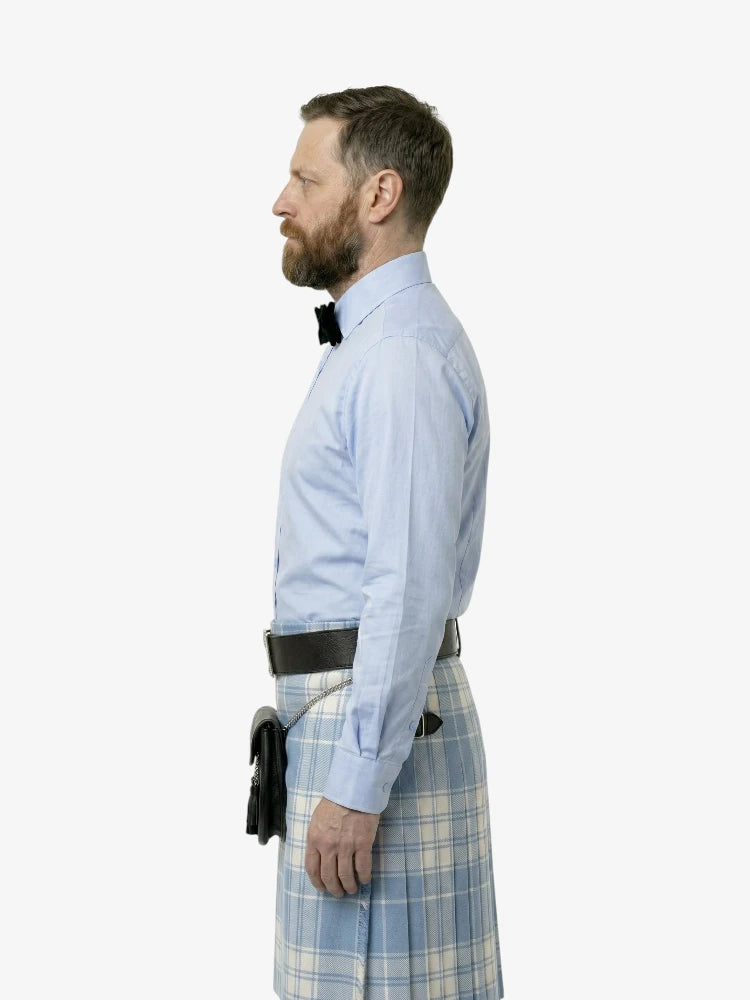 Man wearing a light blue shirt and plaid kilt on a white background