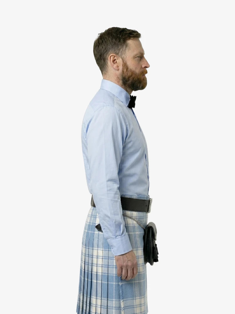 Man wearing a light blue shirt and plaid kilt on a white background