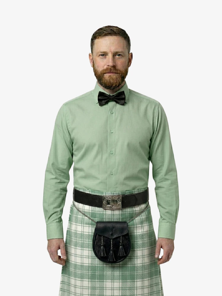 Man wearing a green shirt, bow tie, and tartan kilt on a white background