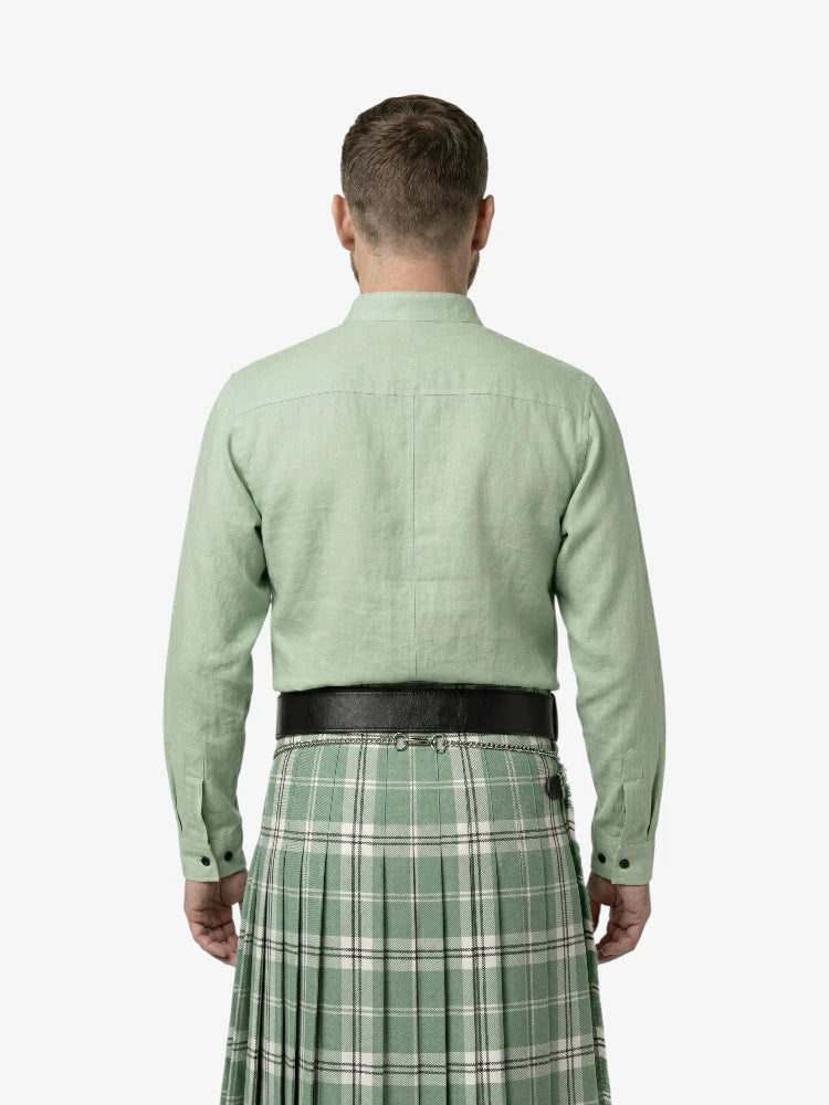 Man wearing a green shirt and plaid kilt on a white background