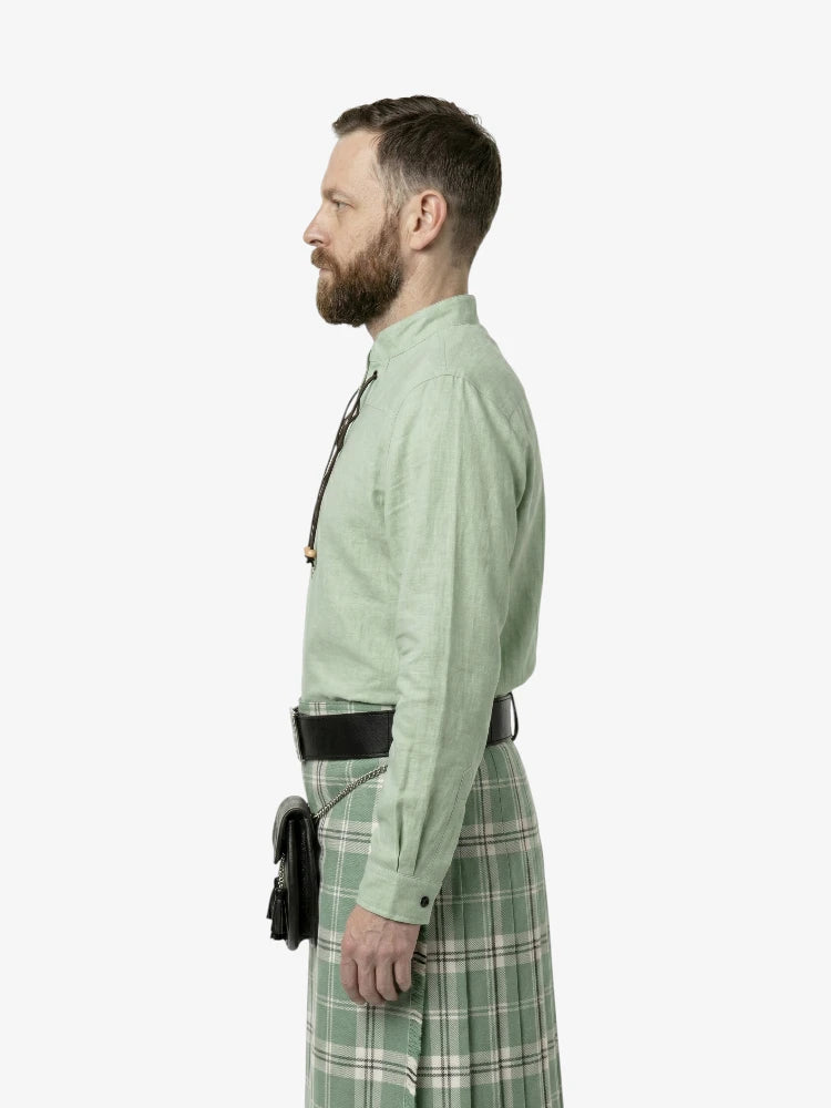 Man wearing a green shirt and plaid kilt on a white background