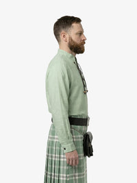 Man wearing a green shirt and plaid kilt on a white background