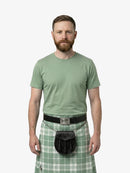 Man wearing a green t-shirt and plaid kilt on a white background
