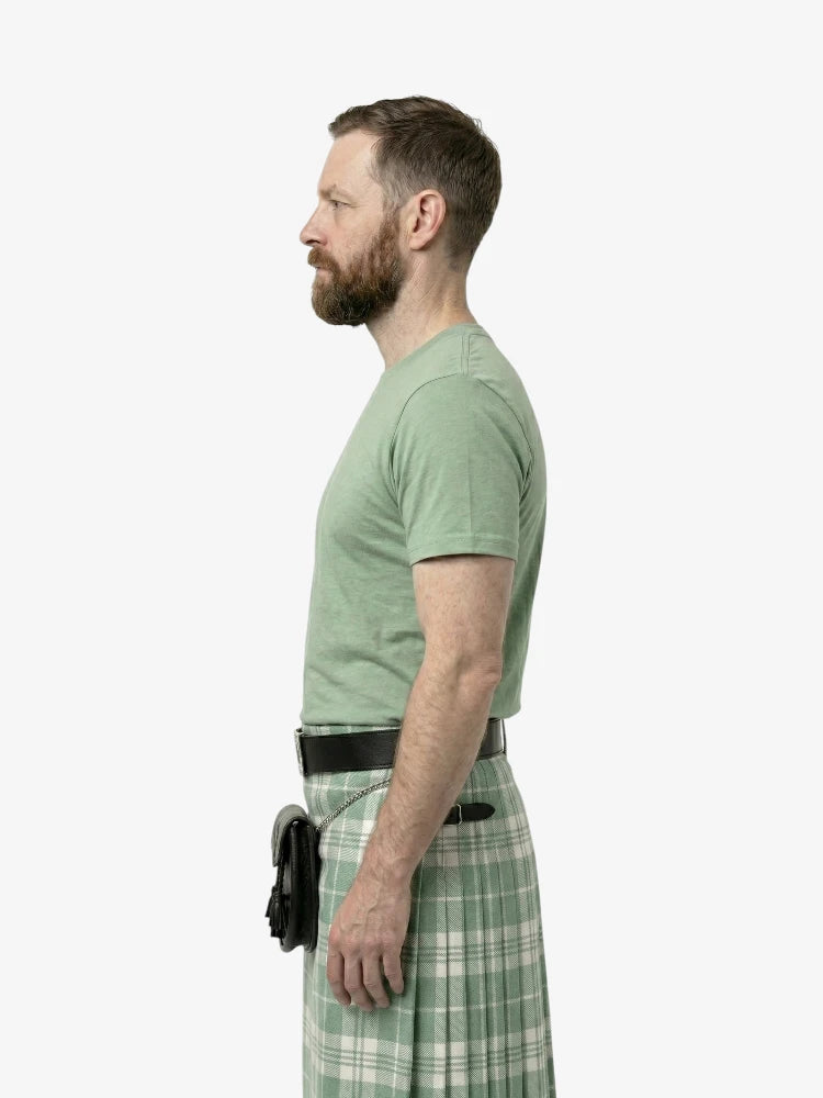 Man wearing a green t-shirt and plaid kilt on a white background