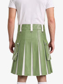 A model from the back wearing a sage green faux-leather pleated kilt with white contrast panels and silver-tone hardware, paired with a white t-shirt.