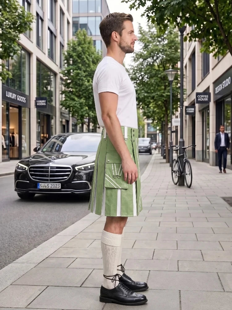 A man stands on a city sidewalk wearing a white crew-neck t-shirt and a light green pleated kilt with white vertical stripe details, paired with cream knee-high socks and black leather shoes. A black Mercedes-Benz car and a bicycle are visible in the background of the urban street scene.