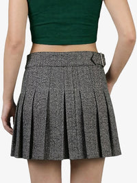 Person wearing a green crop top and pleated skirt on a white background