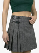 Person wearing a patterned skirt with two buckles on a plain background
