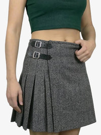 Person wearing a patterned skirt with two buckles on a plain background